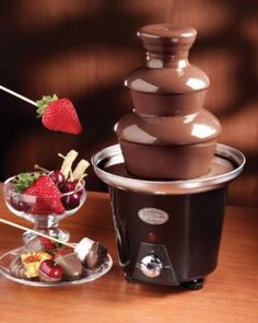 a chocolate fondant fountain with strawberries and other desserts in front of it