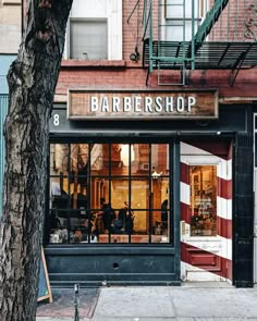 a barber shop on the corner of a street in front of a tree and building