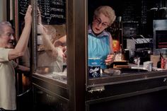 an older woman standing next to a man behind a counter