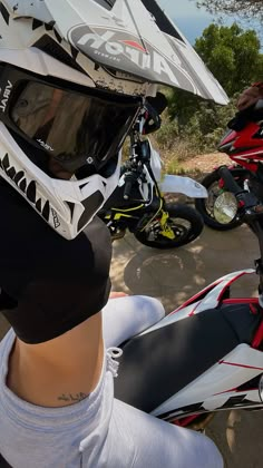 a person wearing a helmet and sitting on a motorbike with another motorcycle in the background