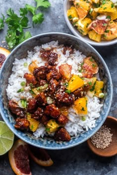 two bowls filled with rice and meat next to sliced oranges, cilantro, and parsley