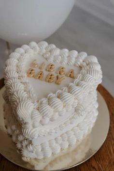 a heart shaped cake sitting on top of a wooden table next to a white balloon