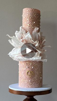 a three tiered pink wedding cake with white and gold decorations on it's side