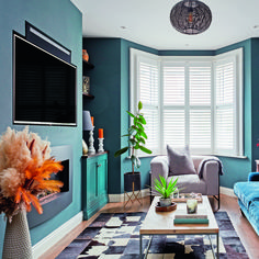 a living room filled with furniture and a flat screen tv mounted on the wall above a fireplace