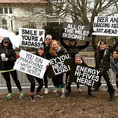 a group of people holding up signs in front of a fence with trees behind them