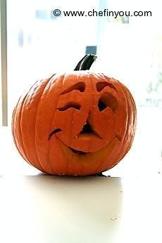 a carved pumpkin sitting on top of a white table next to a window with the words happy halloween written in it