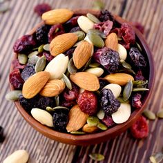 a wooden bowl filled with nuts and raisins on top of a wood table