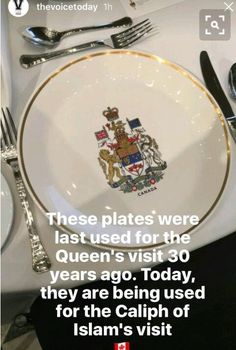 a white plate topped with a royal crest on top of a table next to silverware