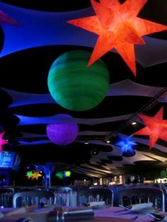 the ceiling is decorated with colorful lights and stars hanging from it's sides, along with tables and chairs