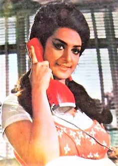 a woman talking on a red phone while holding a white object in her right hand