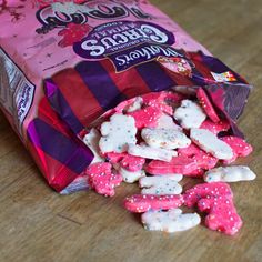 a bag of pink and white cookies sitting on top of a wooden table next to a candy bar