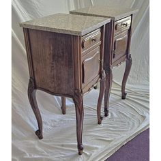 two wooden nightstands with marble top on white sheeted floor next to each other