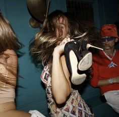 a woman holding up a pair of shoes in front of her face while others look on