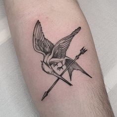 a black and white tattoo of a bird with an arrow on it's arm