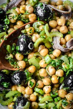 a bowl filled with black eyed peas, broccoli and other vegetables next to a wooden spoon