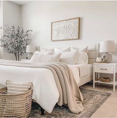 a bedroom with white bedding and wicker baskets on the floor next to it