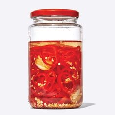 a glass jar filled with red liquid and sliced onions