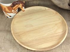 a wooden plate with a horse figurine on it next to a coffee cup