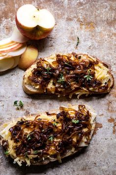 two pieces of bread covered in toppings next to an apple