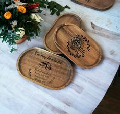 three wooden trays sitting on top of a table with flowers and greenery in the background