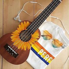 a ukulele and sunglasses on top of a wooden floor next to a string bag