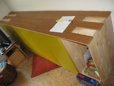 a desk made out of plywood and wood with a red pillow on the floor next to it