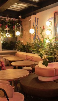 the interior of a restaurant with round tables and planters on the wall above them