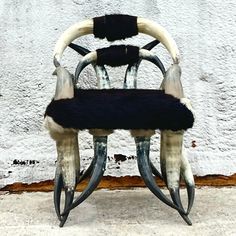 an unusual chair made out of horns and fur is sitting on the ground in front of a white wall