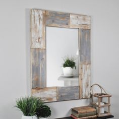 a mirror sitting on top of a wooden shelf next to a potted plant in a white vase