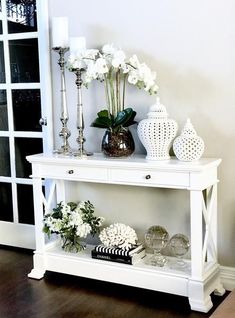 a white table with vases and flowers on it