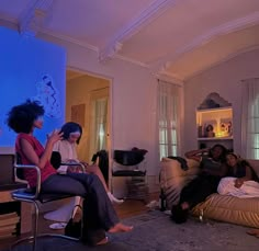 three women sitting on couches in a living room watching something on the tv screen