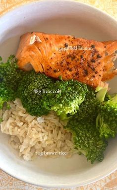 a white bowl filled with rice and broccoli covered in fish fillets on top of it