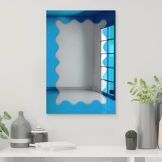 a mirror on the wall above a table with vases and other items in front of it