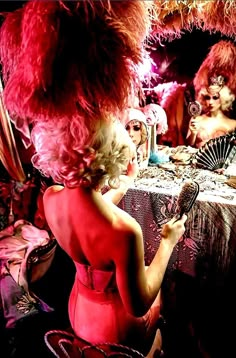 a woman in a red dress is looking at her cell phone and holding a fan