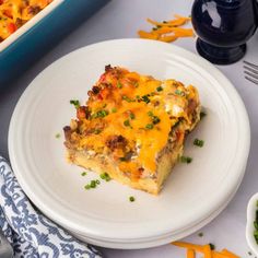 a white plate topped with a piece of casserole next to a bowl of carrots