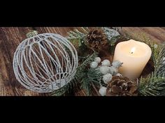 a candle is sitting next to some pine cones and other decorations on a wooden table