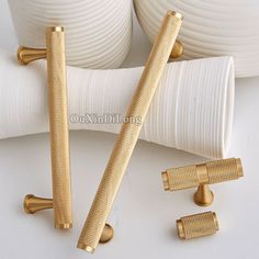 three golden handles and two white vases on a white table with gold trimming