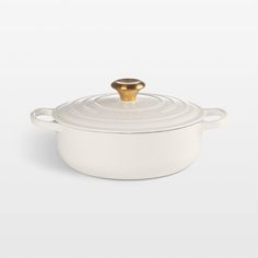 a white casserole with a gold knob on the top and bottom, sitting in front of a white background