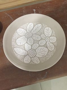 a white plate sitting on top of a wooden table next to a vase and bowl