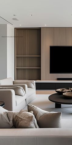 a living room with couches, tables and a flat screen tv on the wall