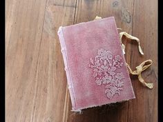 a pink book sitting on top of a wooden floor next to a string and ribbon