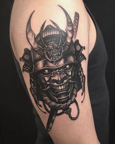 a man with a tattoo on his arm wearing a samurai mask and holding two swords