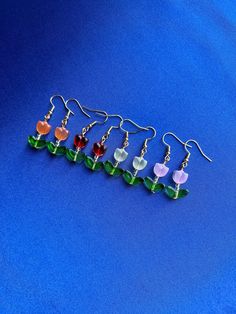 six different colored glass flower earrings on a blue background