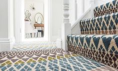 a carpeted stair case with blue and brown designs on it, next to a white staircase