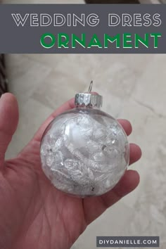 a hand holding a glass ornament with the words wedding dress ornaments on it