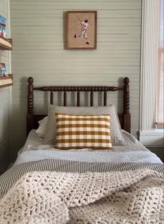 a bed with a blanket and pillows on top of it in a room next to a window