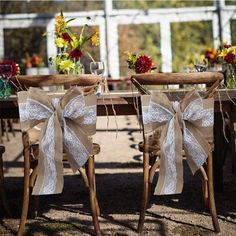 two chairs with bows tied to them are sitting in front of a table set for an outdoor wedding