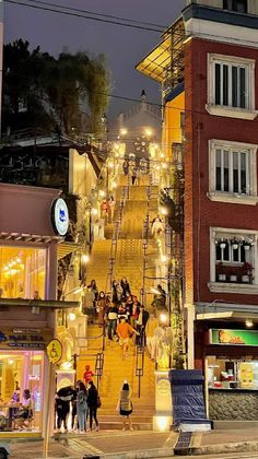 people are walking up and down the stairs in front of some buildings at night time