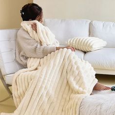 a woman sitting on a couch wrapped in a blanket