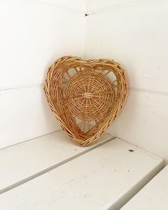 a heart shaped wicker basket sitting on top of a white bench in a room